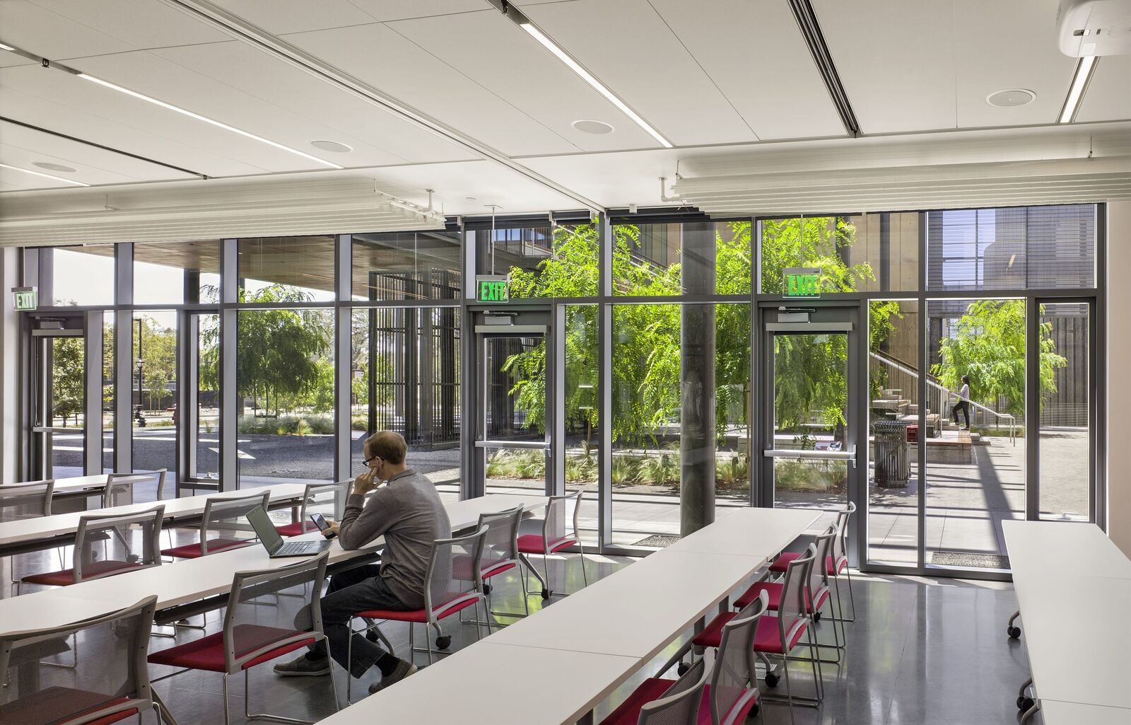 A glass classroom with one student working and tables at the facility. 