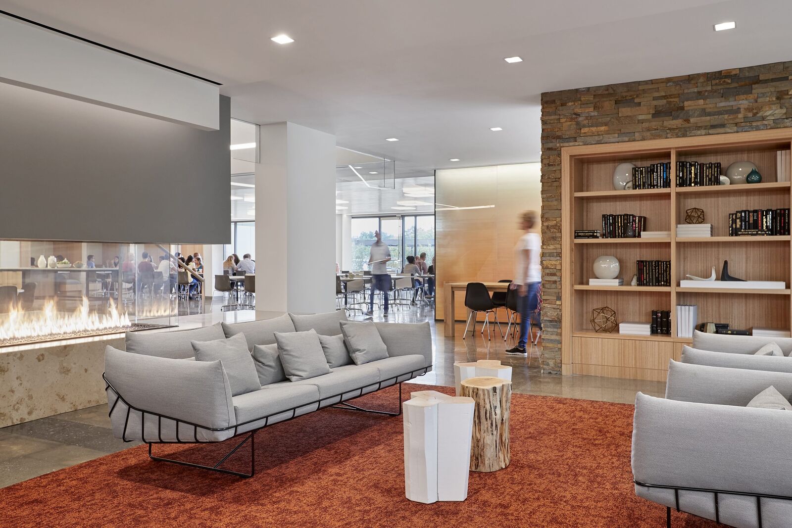 A lounge with two couches surrounded by a fireplace and bookshelves. 