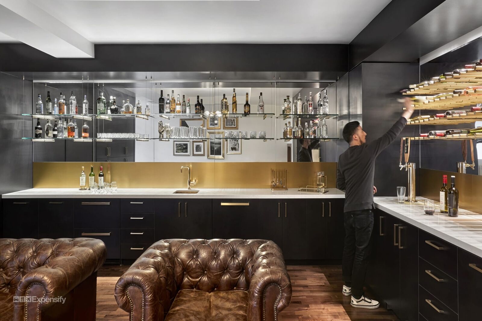 kitchenette style space with leather chairs and various bottles along shelves