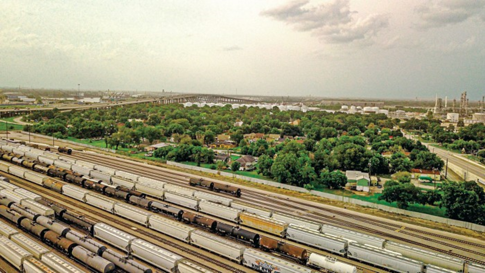 City view of industrial area with train tracks, bridge, and buildings.