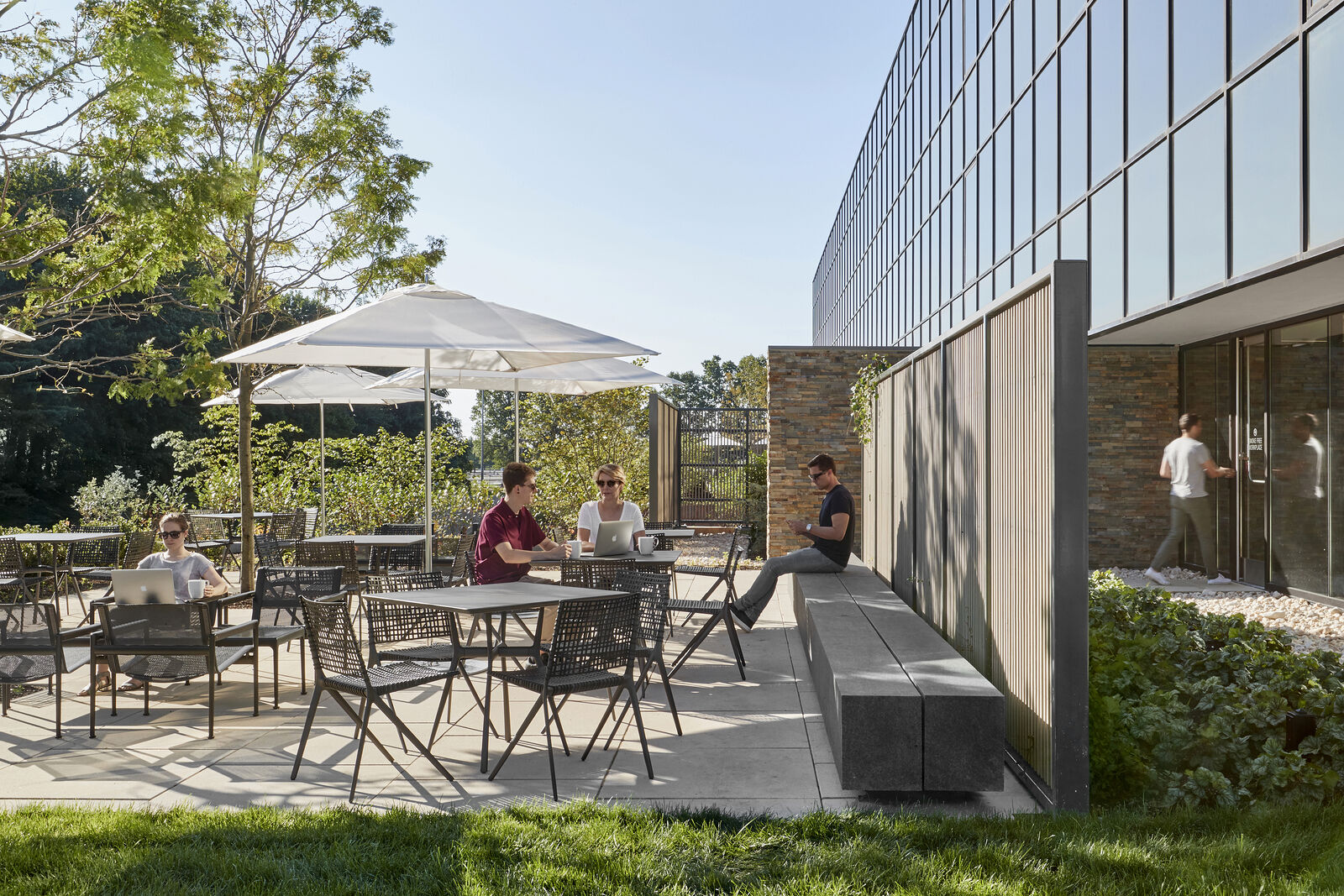The outdoor patio with people talking under umbrellas hanging over the tables. 