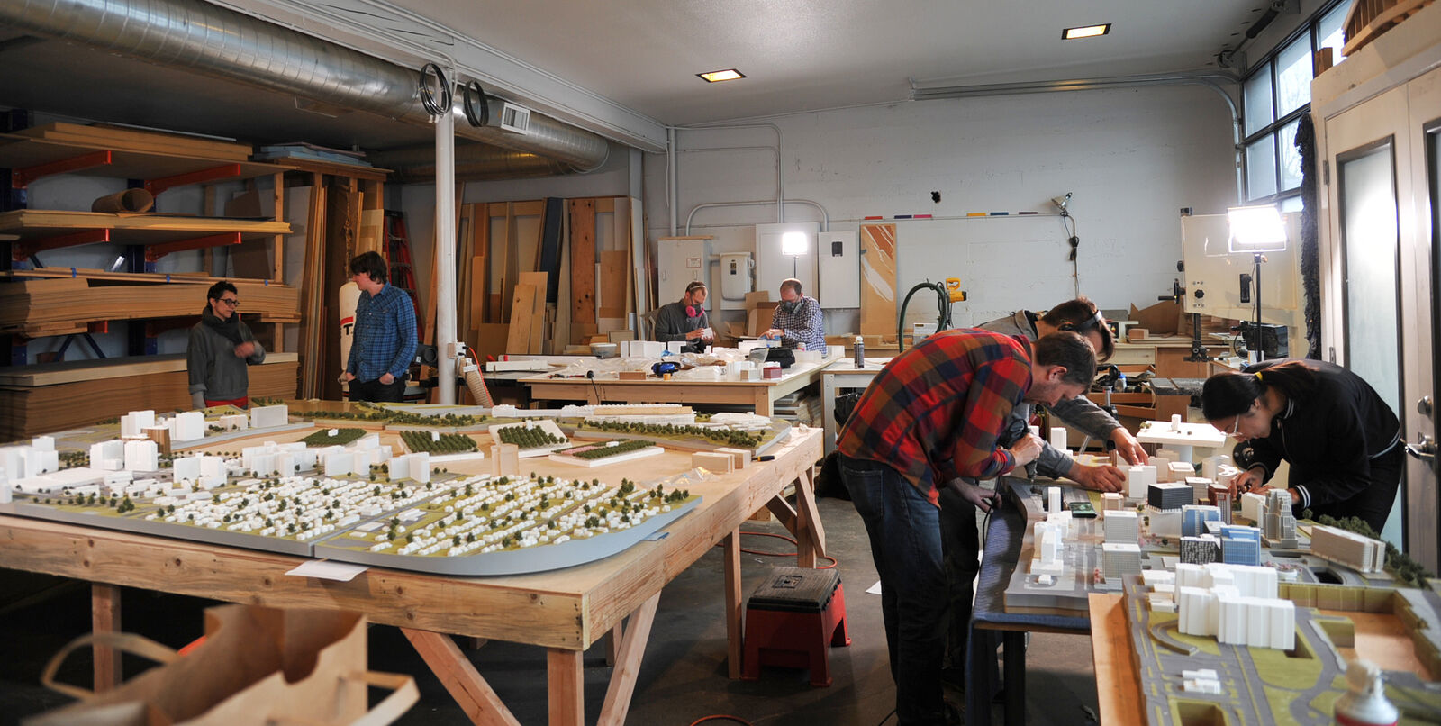group of people working around collection of building models