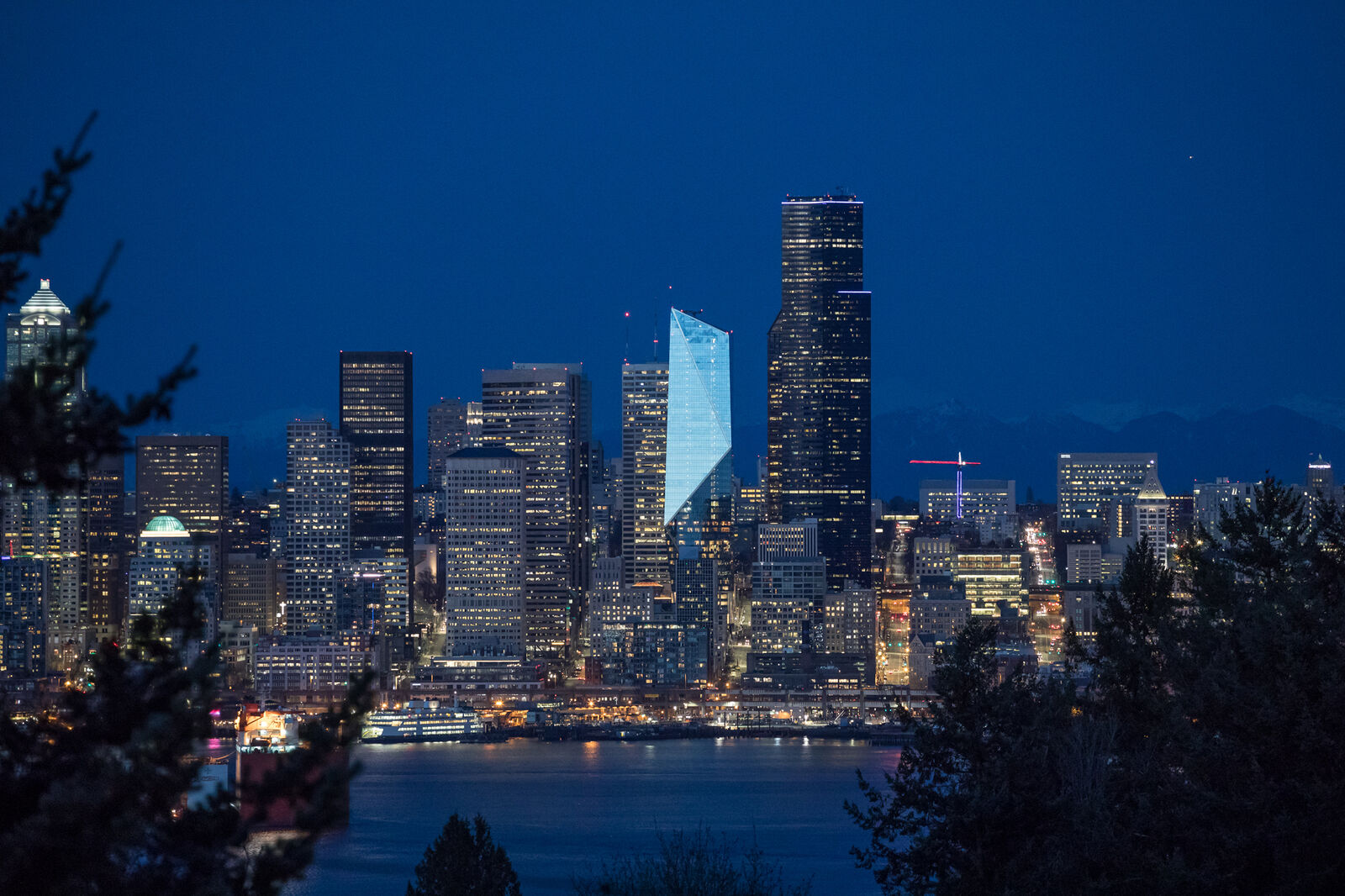 Photo of the Seattle skyline at night with light reflecting off the F5 Tower, making it stand out against the other buildings
