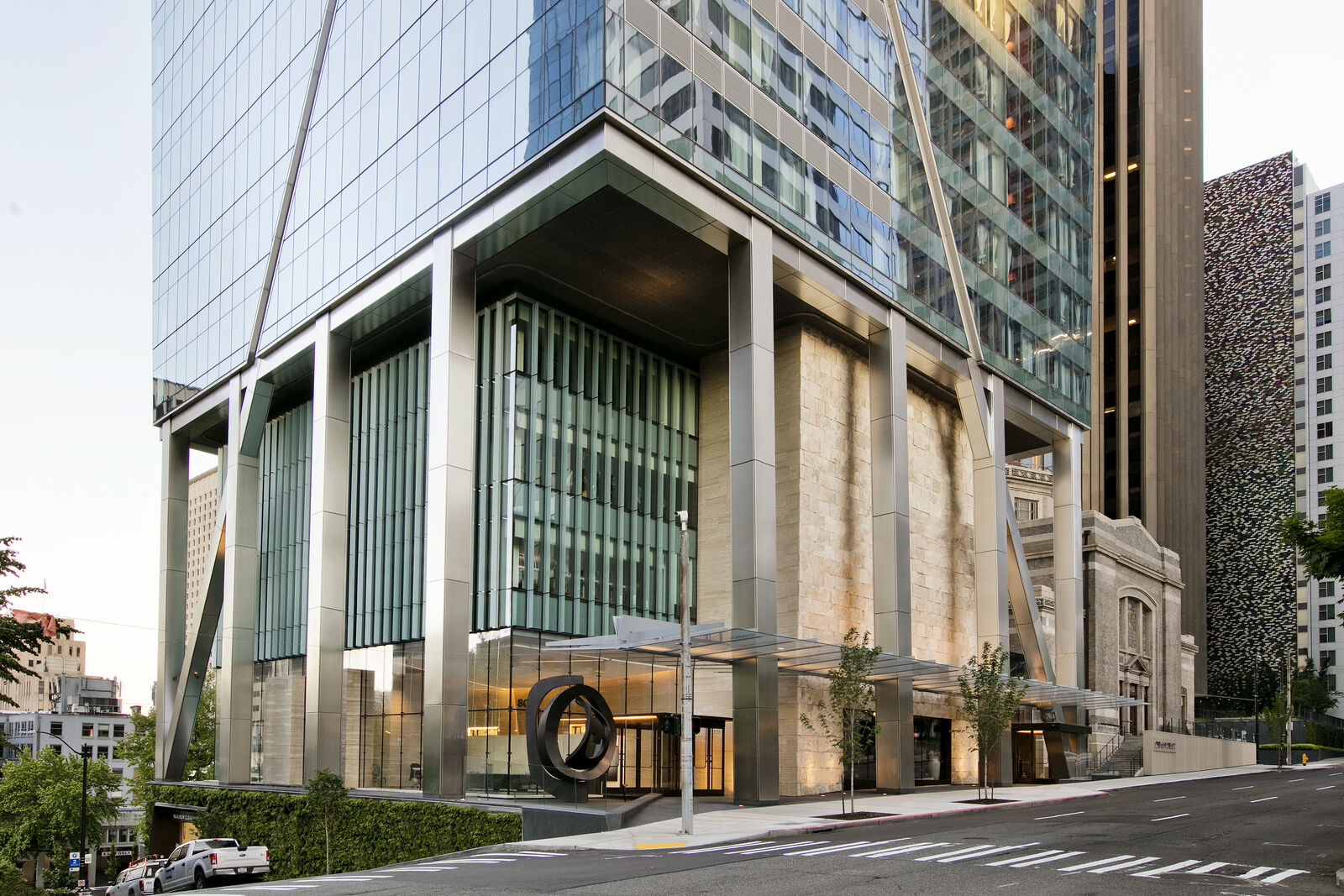 Exterior photo of the base of F5 Tower at the corner of 5th Ave and Marion Street, showing how the podium meets the ground at an incline on the hill