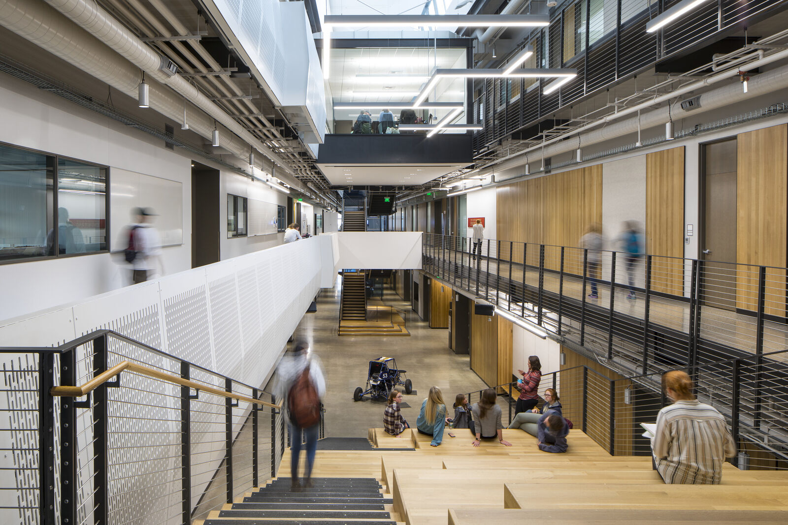 Interior photo of staircase in the atrium of Norm Asbjornson Hall with students sitting and walking down the stairs