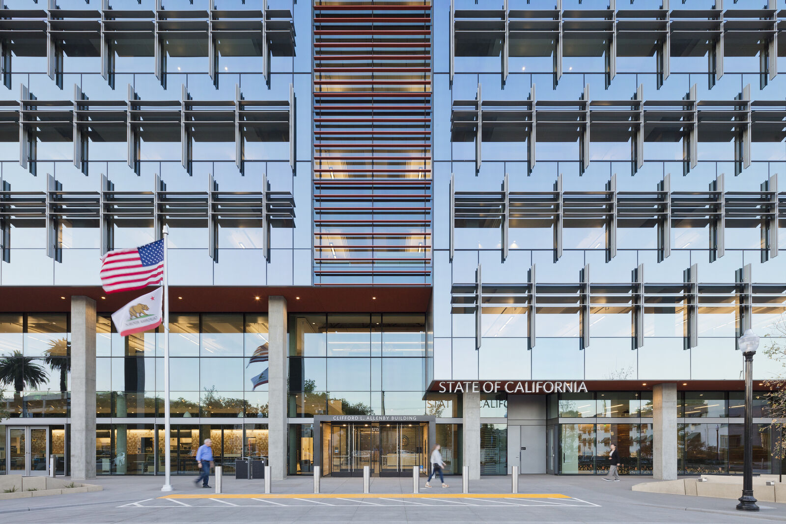 Front entrance of building with flags flying to the side.