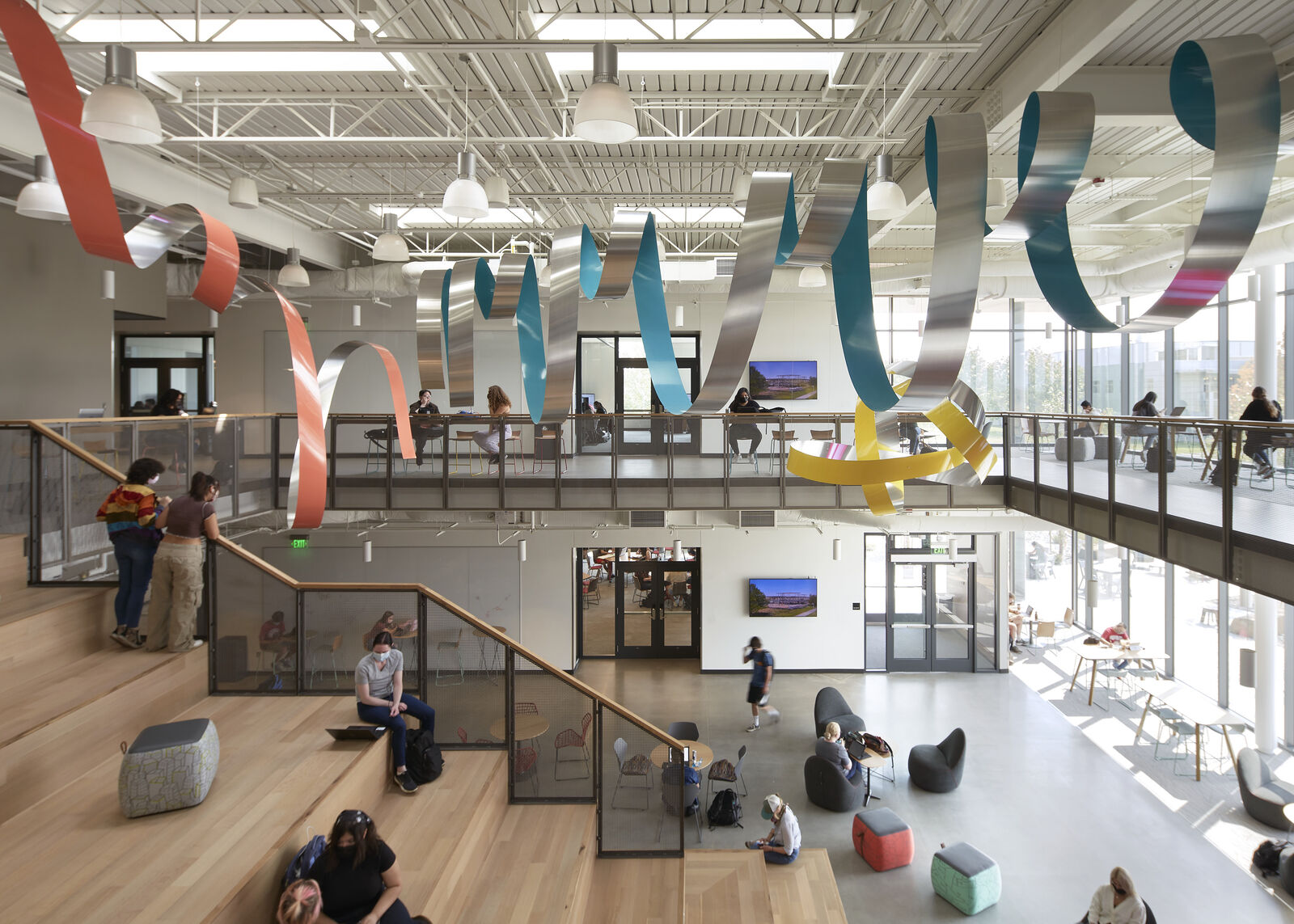 lobby area with staircase and large, colorful sculpture hanging on ceiling. 